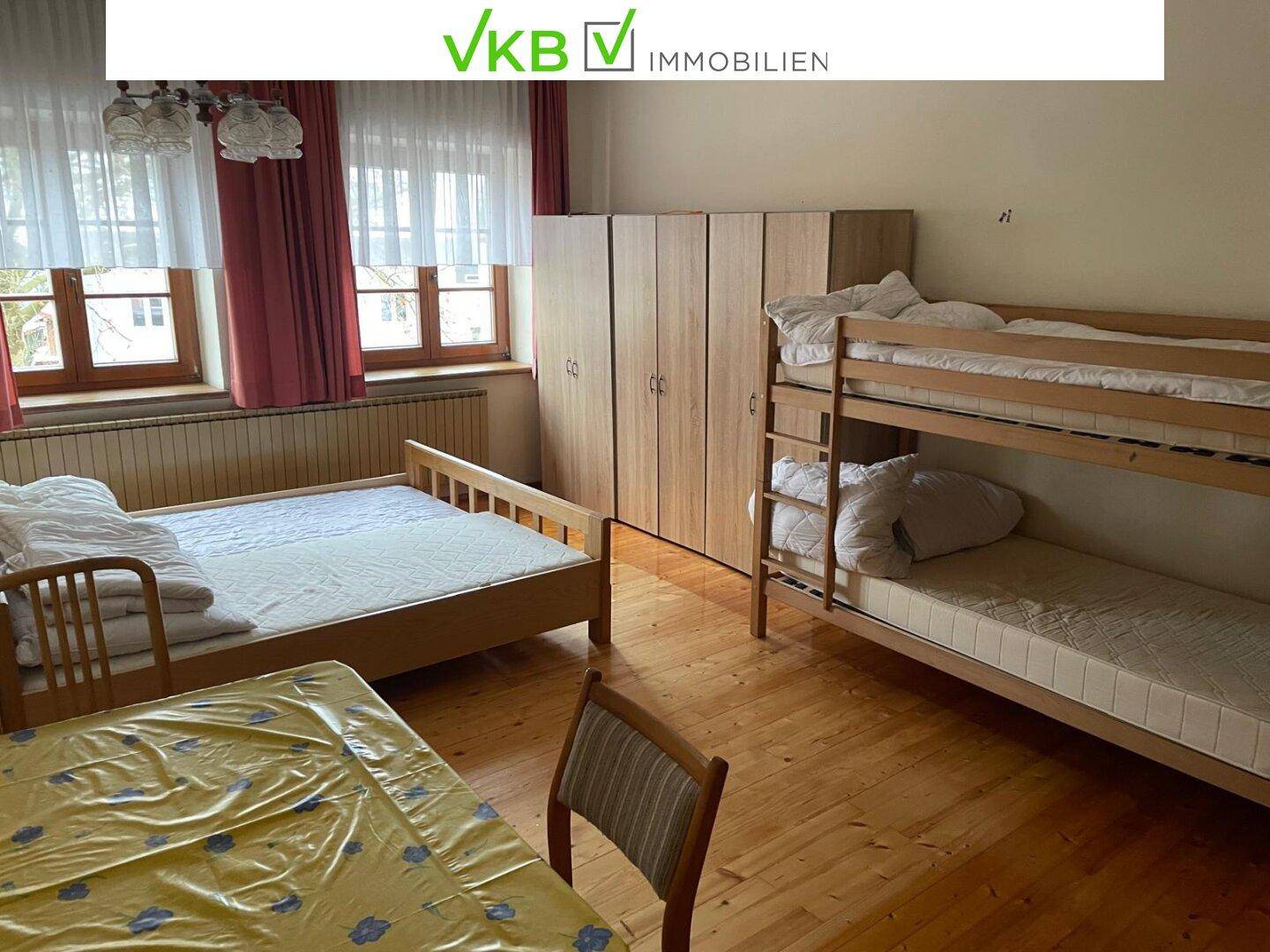 Geräumiges Schlafzimmer mit Holzboden, Etagenbetten und einem Esstisch, hell und funktional.