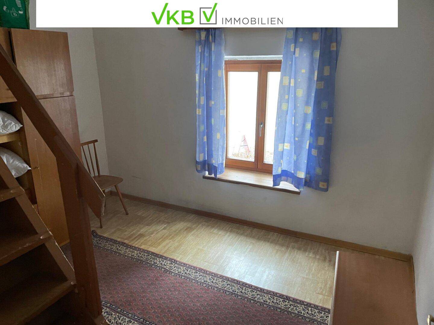Schlafzimmer mit Holzboden, einem Fenster und einer Holztreppe, die zu einem Hochbett führt.