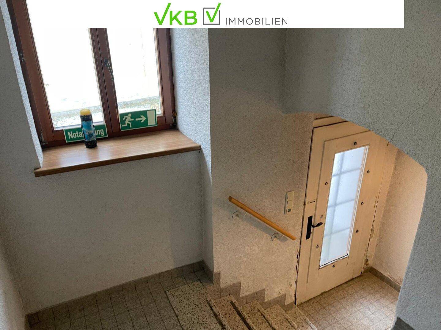 Treppenaufgang mit Terrazzoboden und Holzgeländer, führt zu einer weiteren Etage des Hauses.