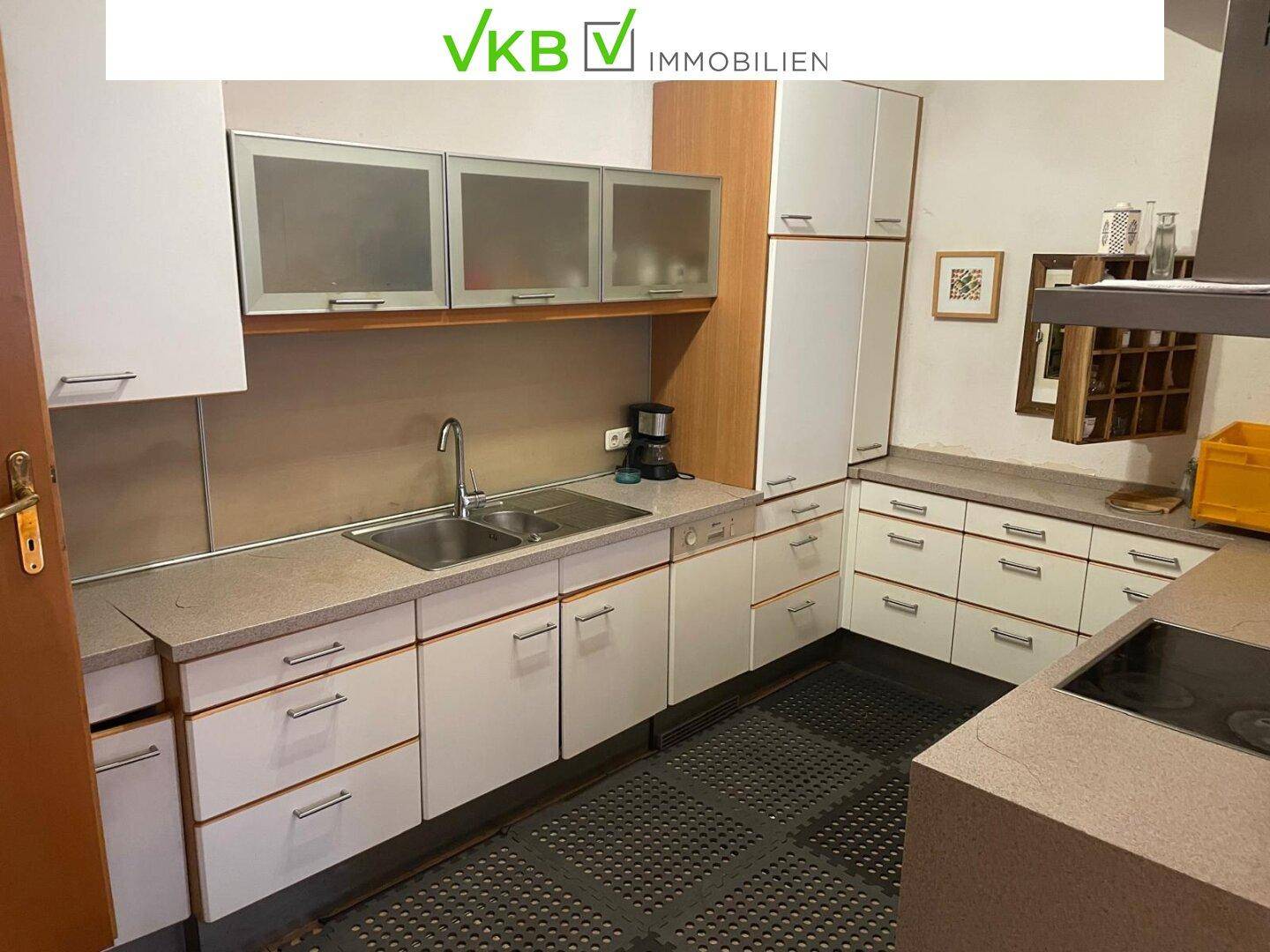 Moderne Küche mit weißen Schränken, Doppelspüle, Herd und Dunstabzugshaube, gut ausgestattet.