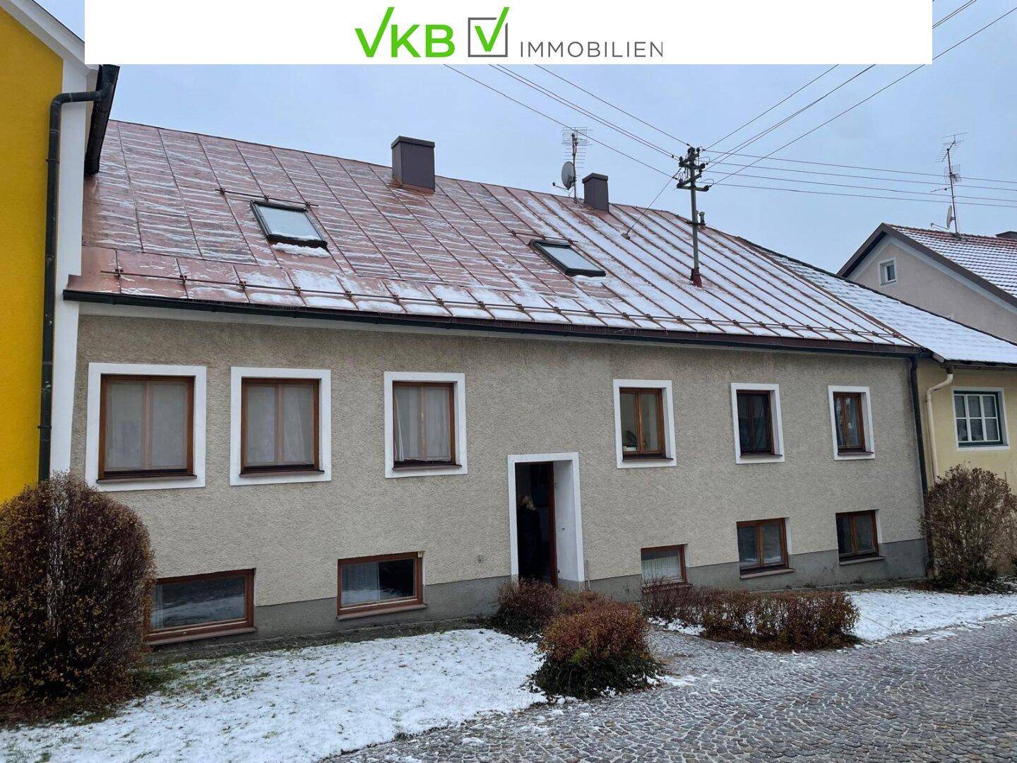 Rückansicht eines Wohnhauses mit mehreren Fenstern und einem Ziegeldach, umgeben von Schnee.