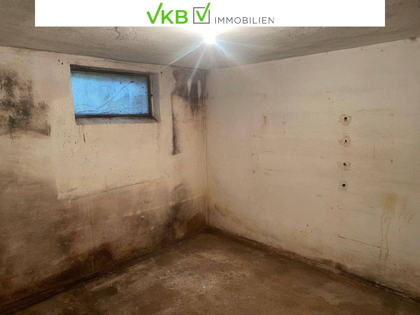 Kellerraum mit kleinem Fenster und unfertigen Wänden, ideal als Lagerfläche.