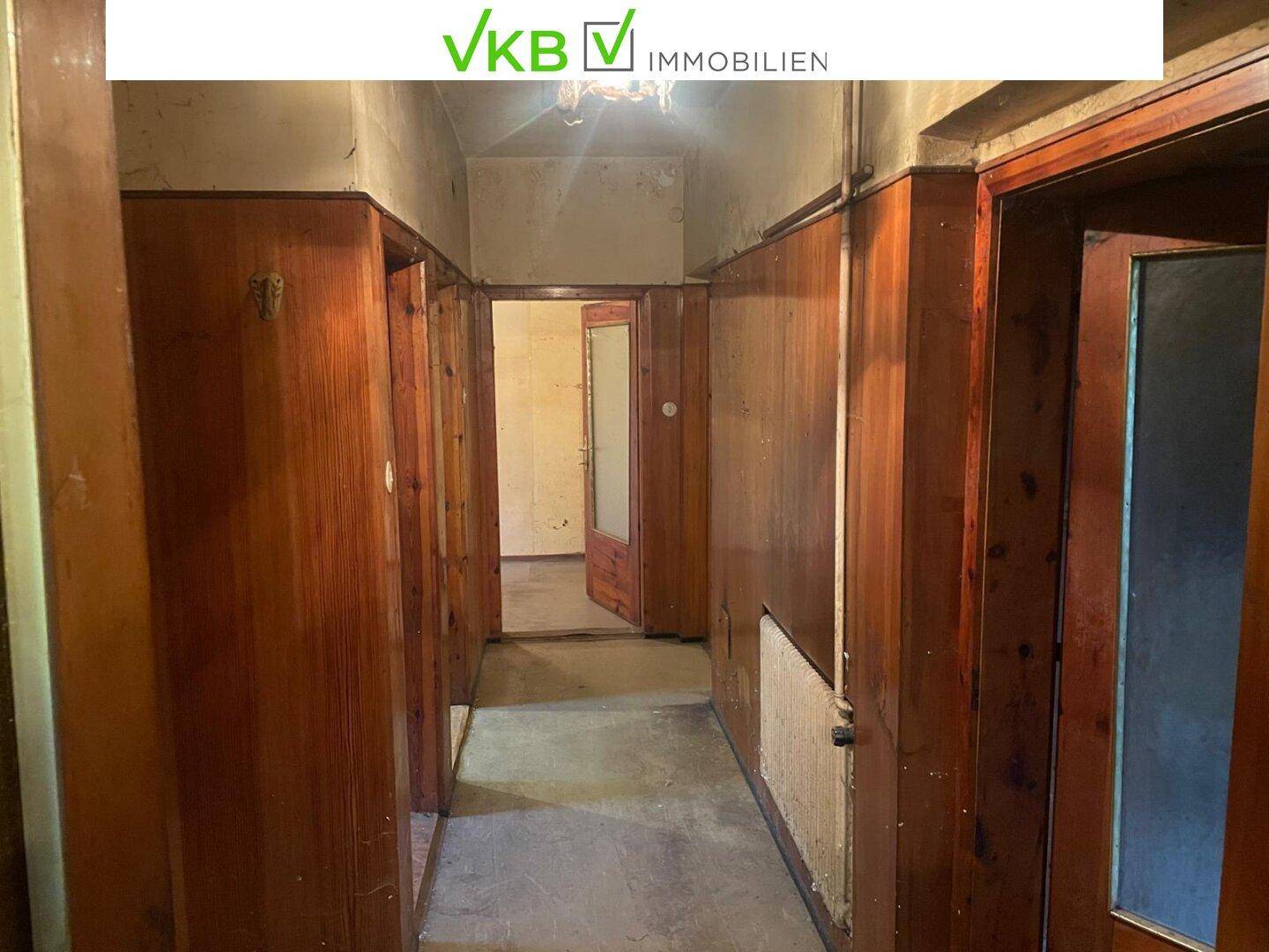 Langer Flur mit Holzvertäfelung und mehreren Türen, im ursprünglichen Zustand.
