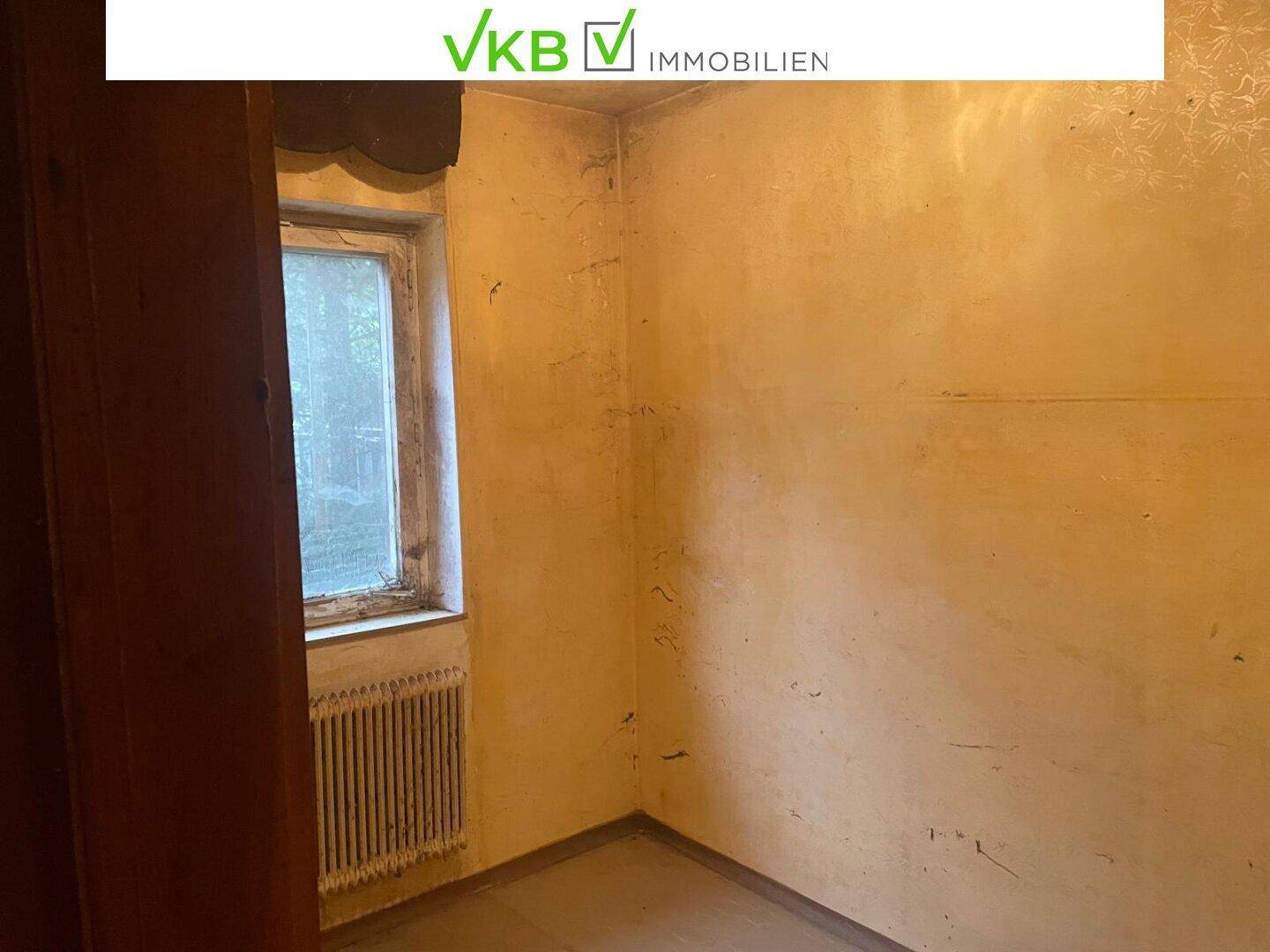 Leerer Raum mit Fenster und Heizkörper, benötigt umfassende Renovierung.