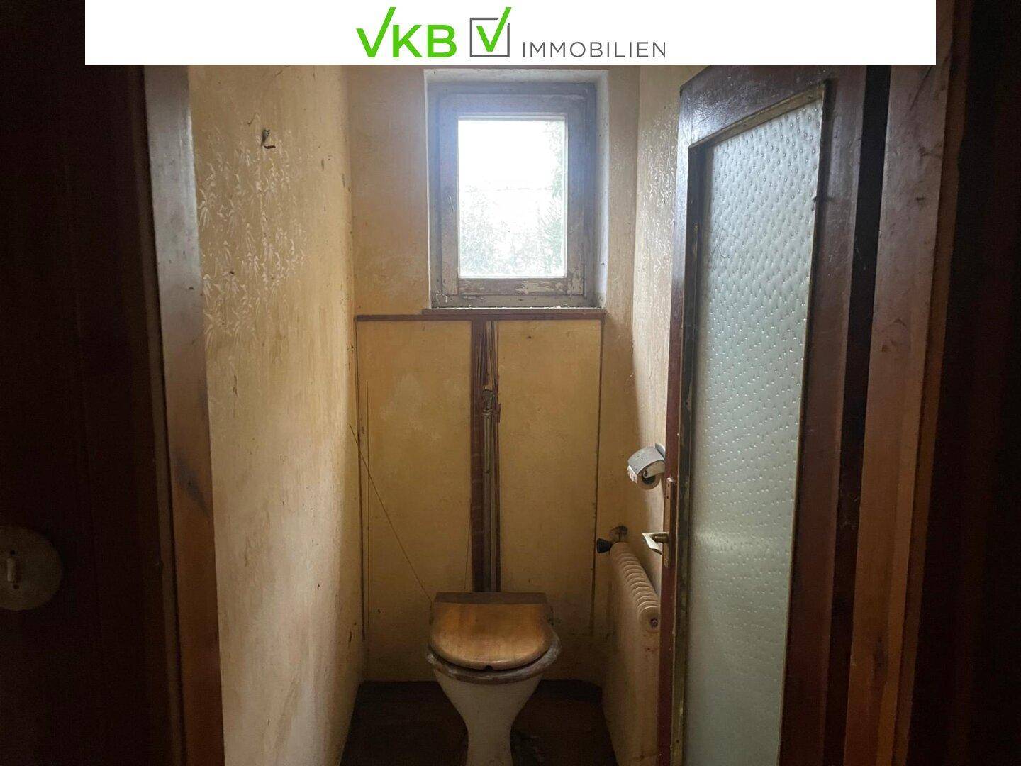 Separate Toilette mit Fenster und einfacher Ausstattung, im ursprünglichen Zustand.
