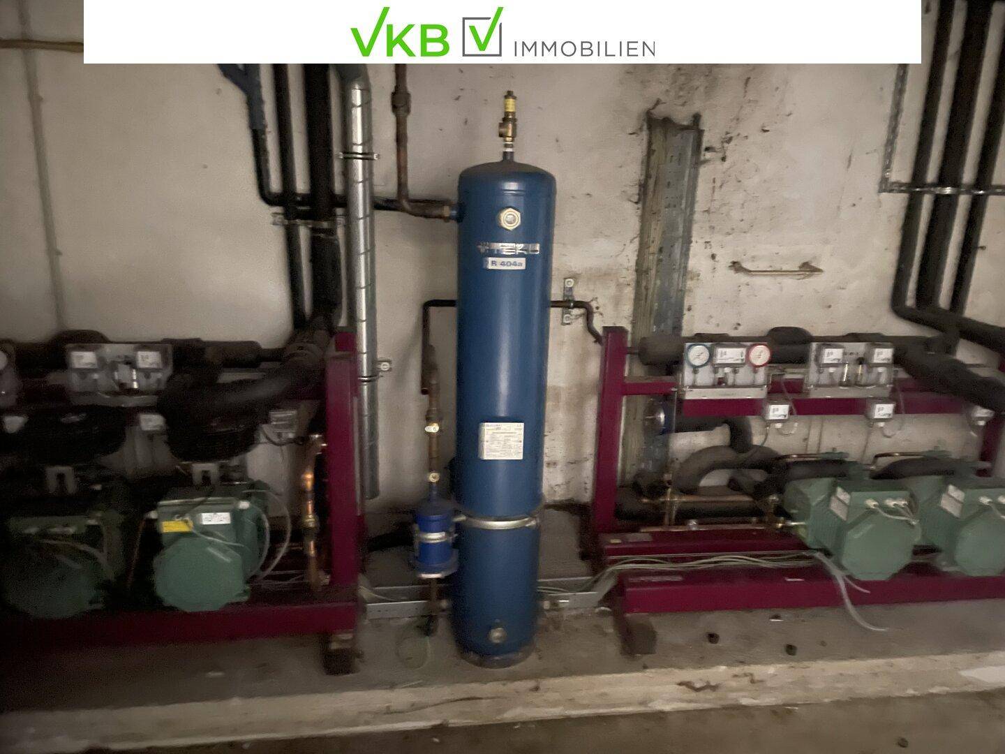Technikraum mit blauen Wassertanks und mehreren Pumpen, die Teil der Gebäudetechnik sind.