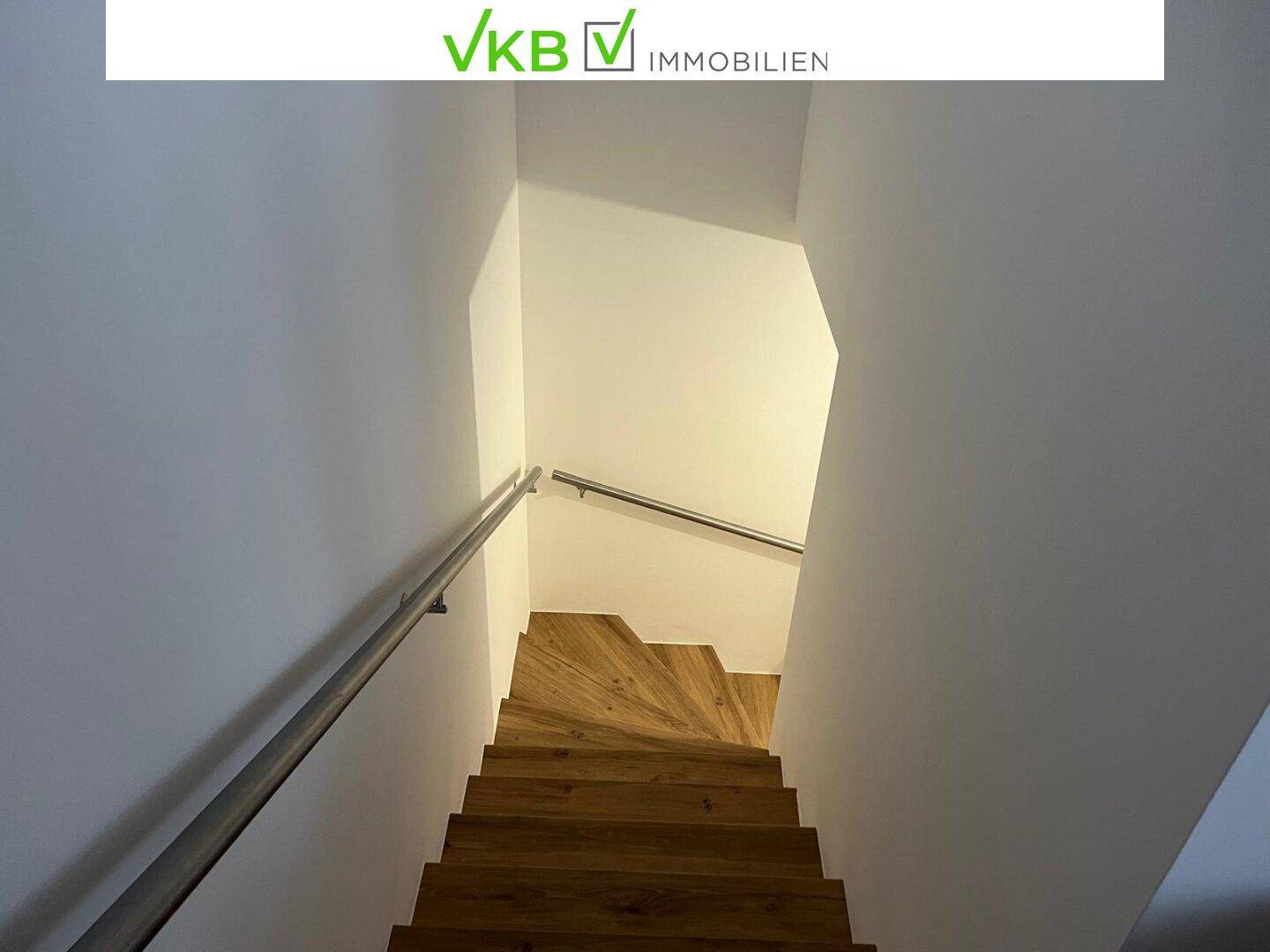 Holztreppe mit modernem Metallgeländer, die in das untere Stockwerk führt.