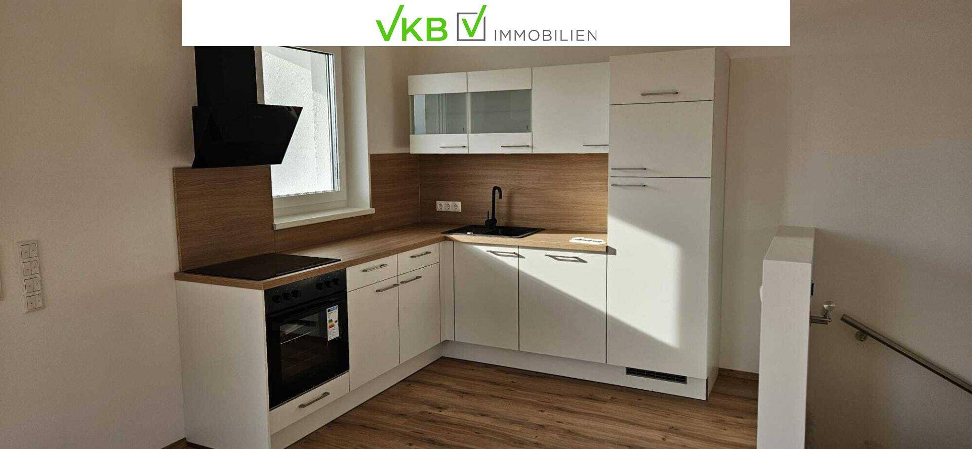 Moderne Einbauküche mit weißen Schränken, Holzarbeitsplatte und integrierten Geräten.