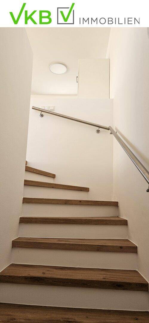 Holztreppe mit modernem Metallgeländer, die in das obere Stockwerk führt.