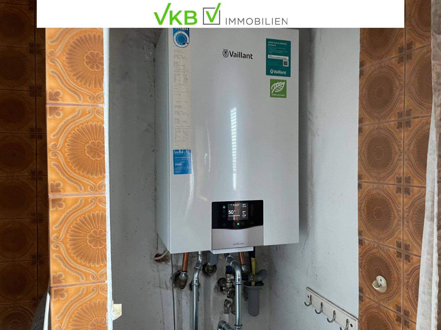 Moderner Warmwasserbereiter von Vaillant in einem Badezimmer mit braunen Fliesen.