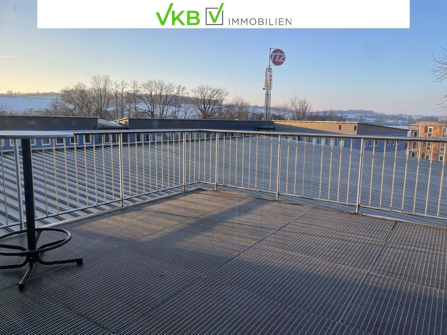 Weitläufige Dachterrasse mit Blick auf die umliegende Landschaft und einen Mobilfunkmast.