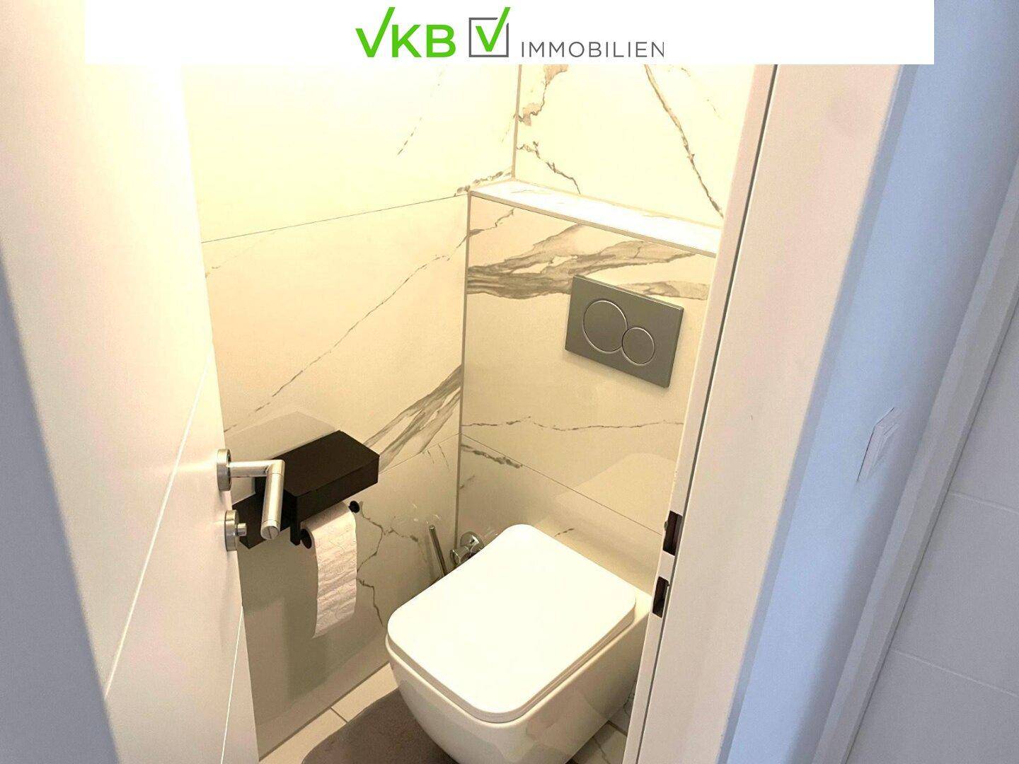 Separates WC mit Wand-WC und stilvollen Marmoroptik-Fliesen.