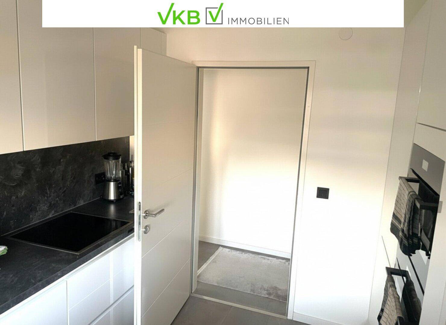 Funktionale Küche mit weißen Fronten und Zugang zu einem praktischen Abstellraum.