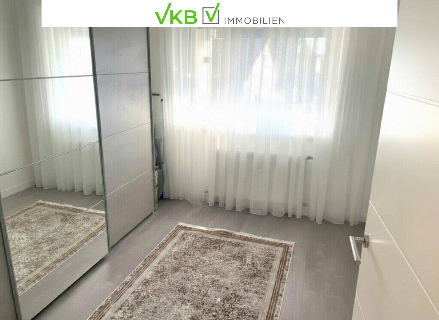 Schlafzimmer mit Laminatboden, Spiegelschrank und Fenster mit viel Tageslicht.