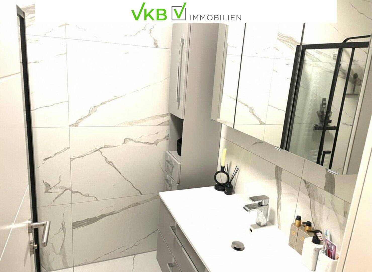 Modernes Badezimmer mit Marmorfliesen, Einzelwaschbecken und Spiegelschrank.
