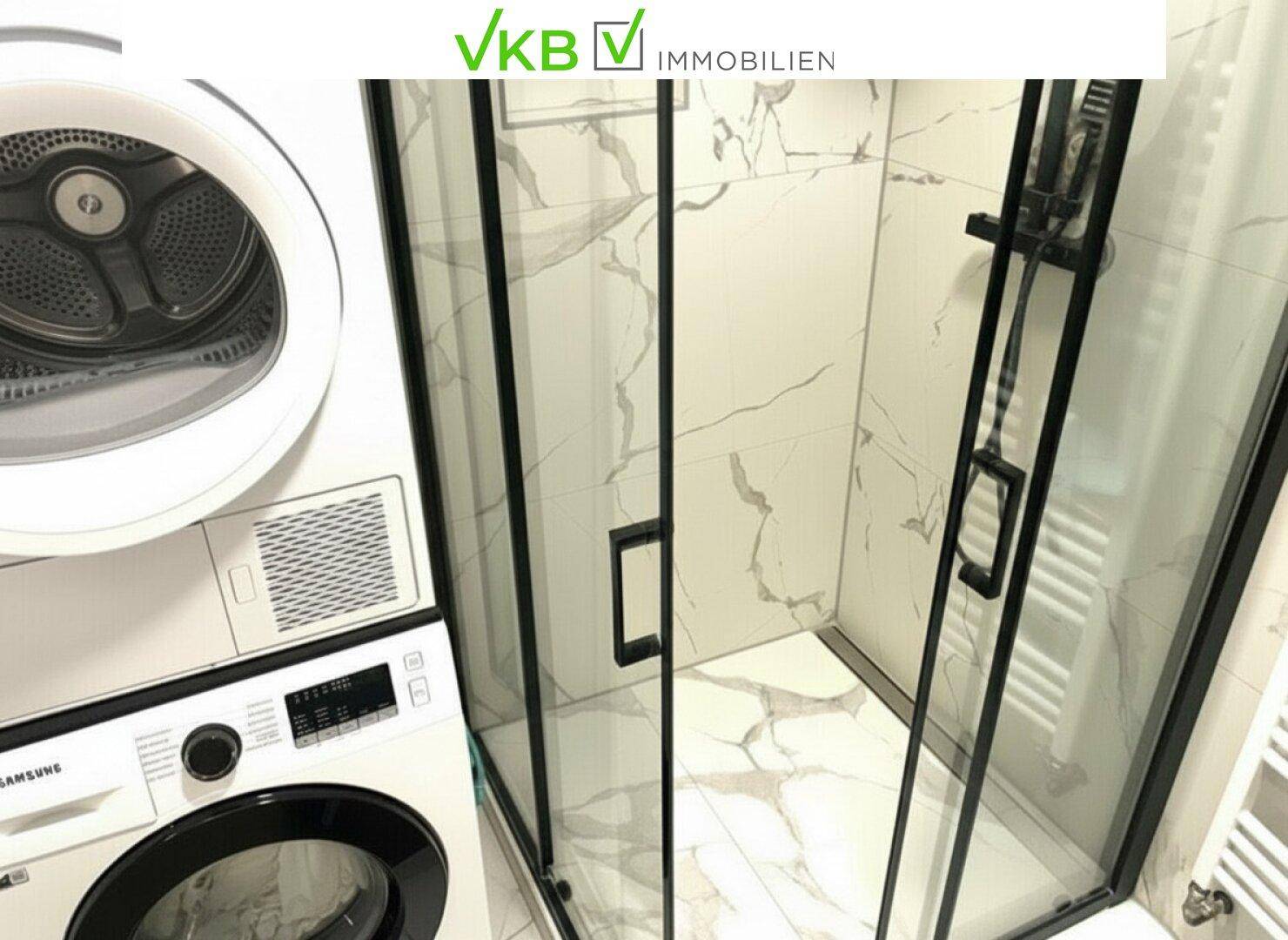 Badezimmer mit moderner Duschkabine, Waschmaschine und Trockner.
