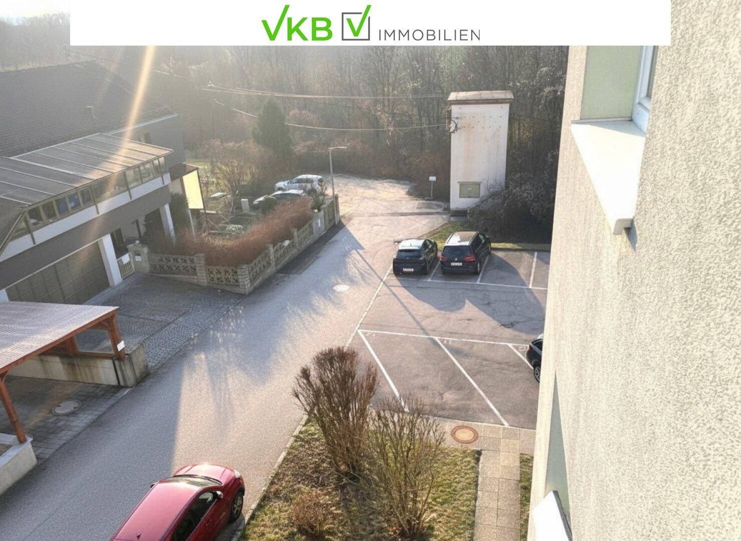 Blick vom Balkon auf den Parkplatz und die umliegenden Gebäude.