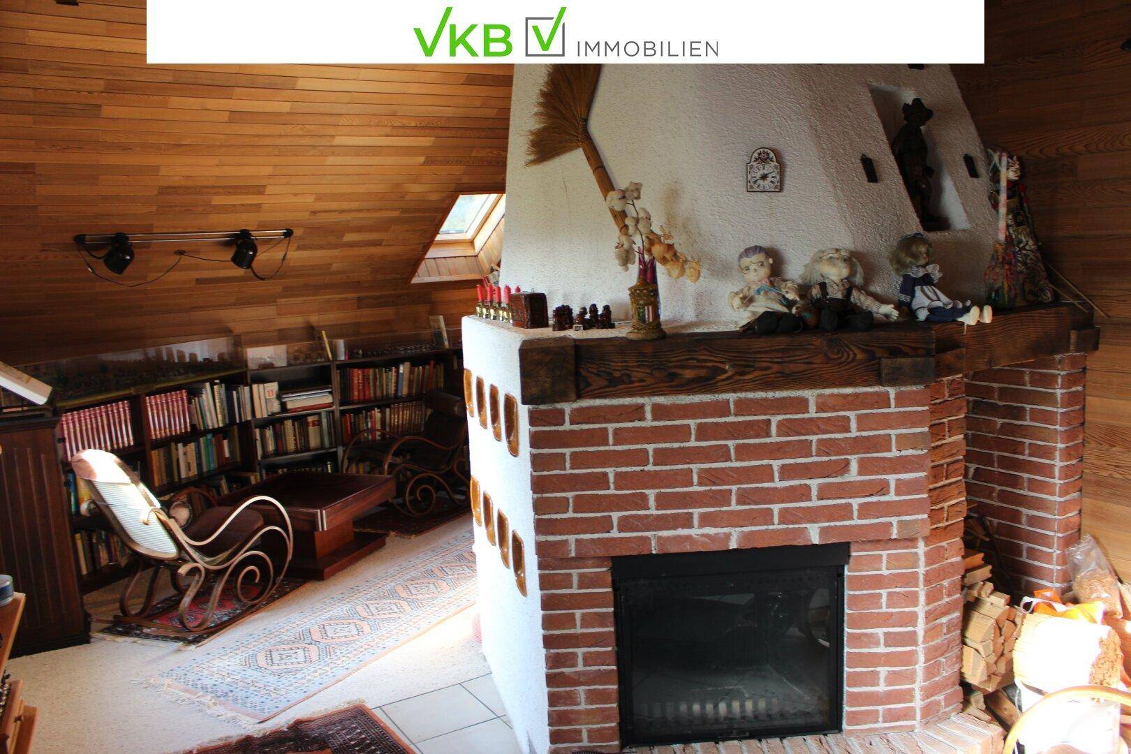 Gemütlicher Wohnbereich mit einem gemauerten Kamin und Holzverkleidung an Decke und Wänden.