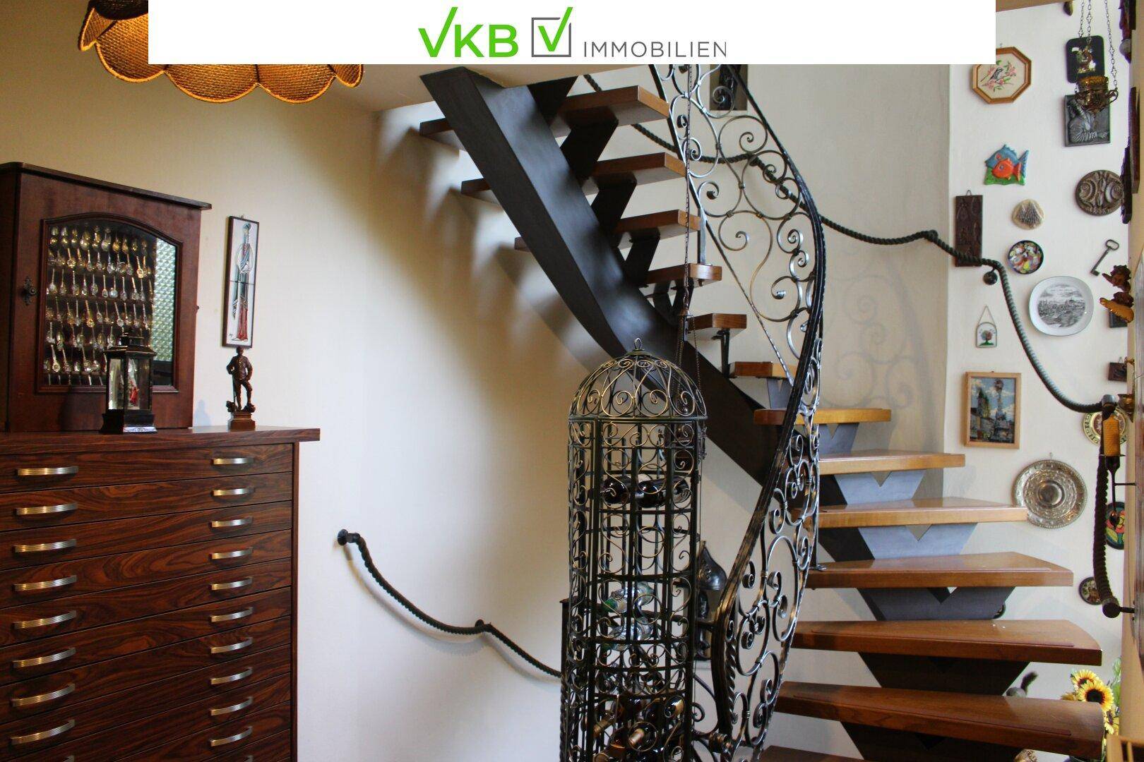 Elegante Wendeltreppe mit schmiedeeisernem Geländer und Holzstufen in einem Flur.
