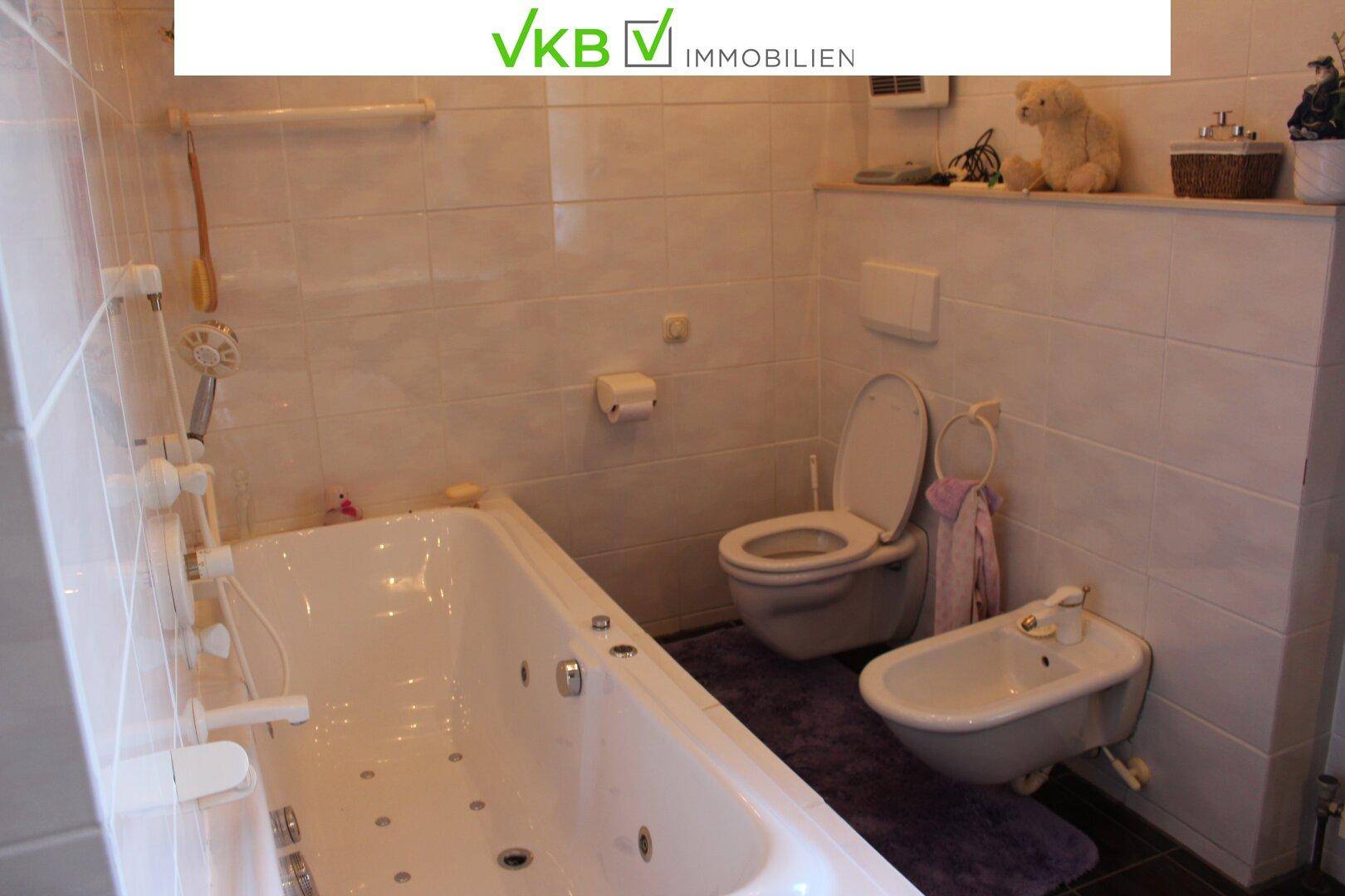 Badezimmer mit Whirlpool-Badewanne, Toilette und Bidet, komplett gefliest.
