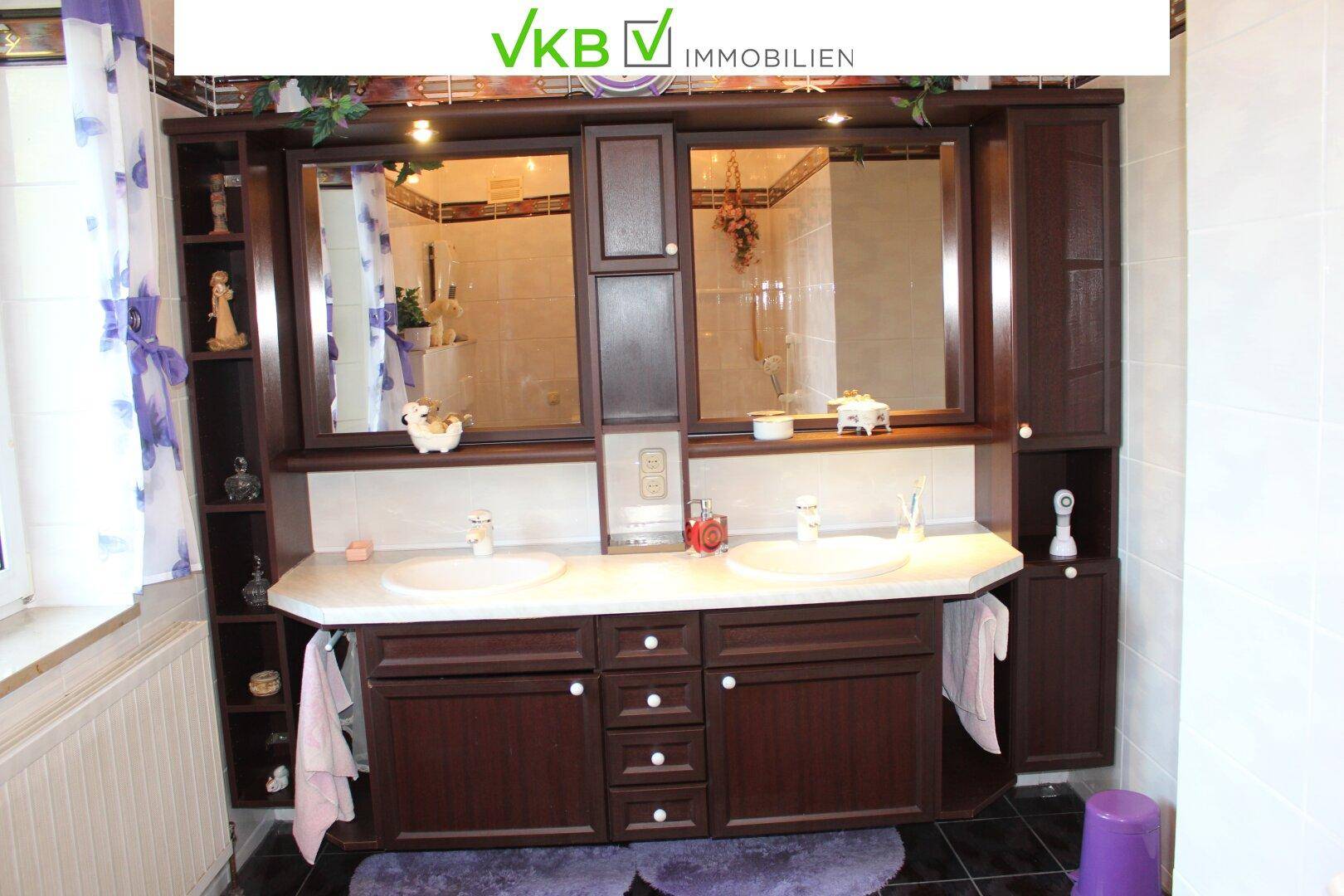 Geräumiges Badezimmer mit Doppelwaschbecken, großem Spiegelschrank und dunklen Holzmöbeln.