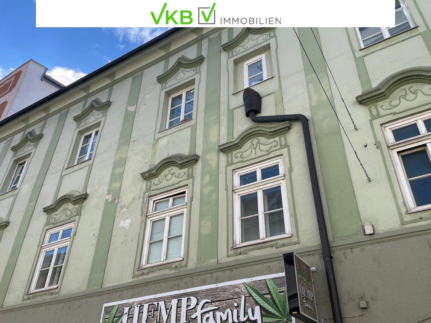 Nahaufnahme einer historischen Fassade mit dekorativen Fenstern und einer Regenrinne.