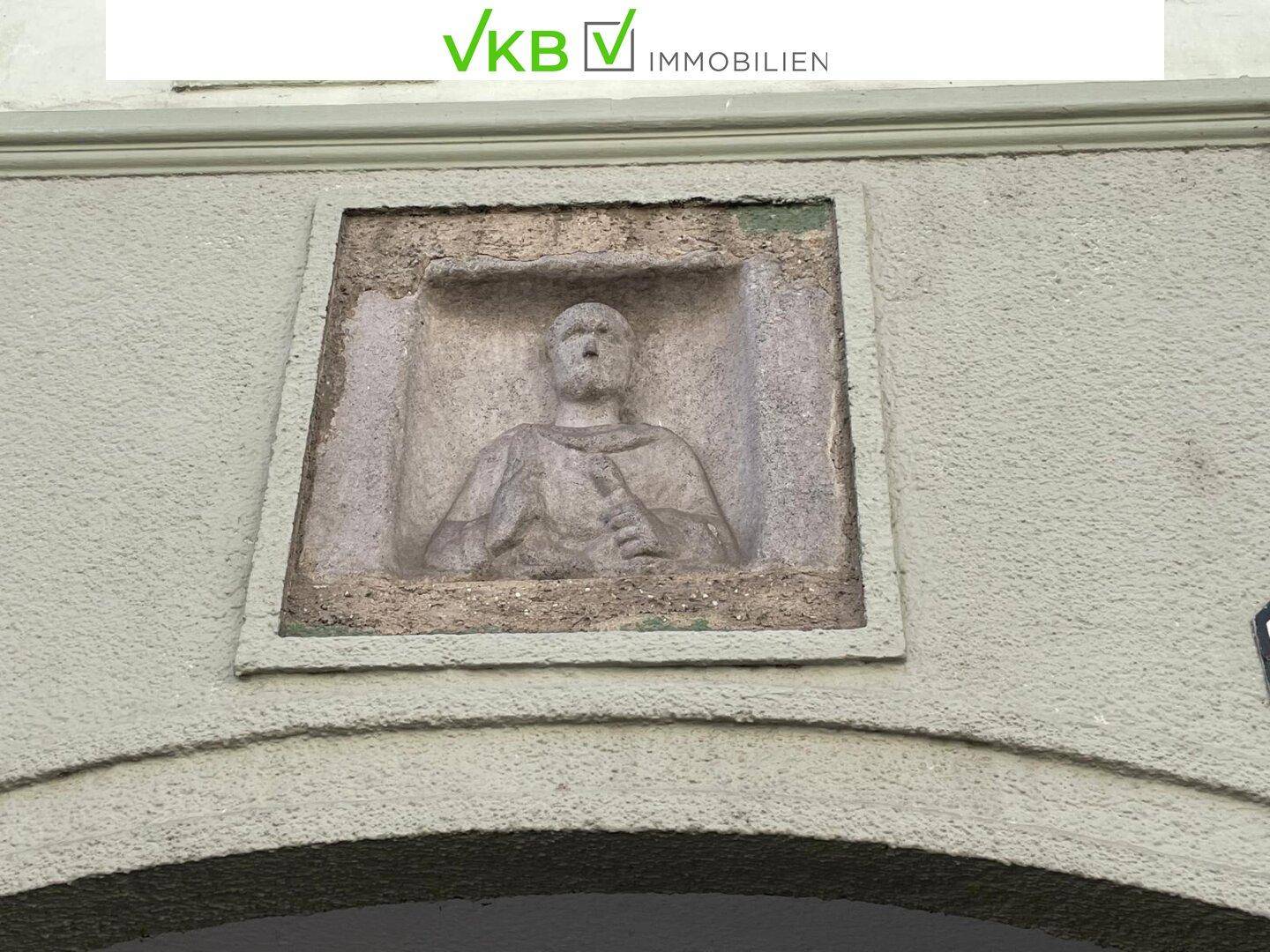 Ein eingemauertes Steinrelief mit einer figürlichen Darstellung an der historischen Fassade.
