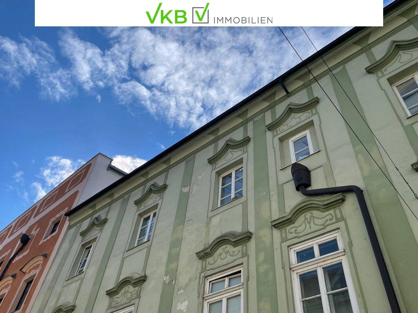 Schräge Ansicht einer historischen Fassade mit verzierten Fenstern unter blauem Himmel.
