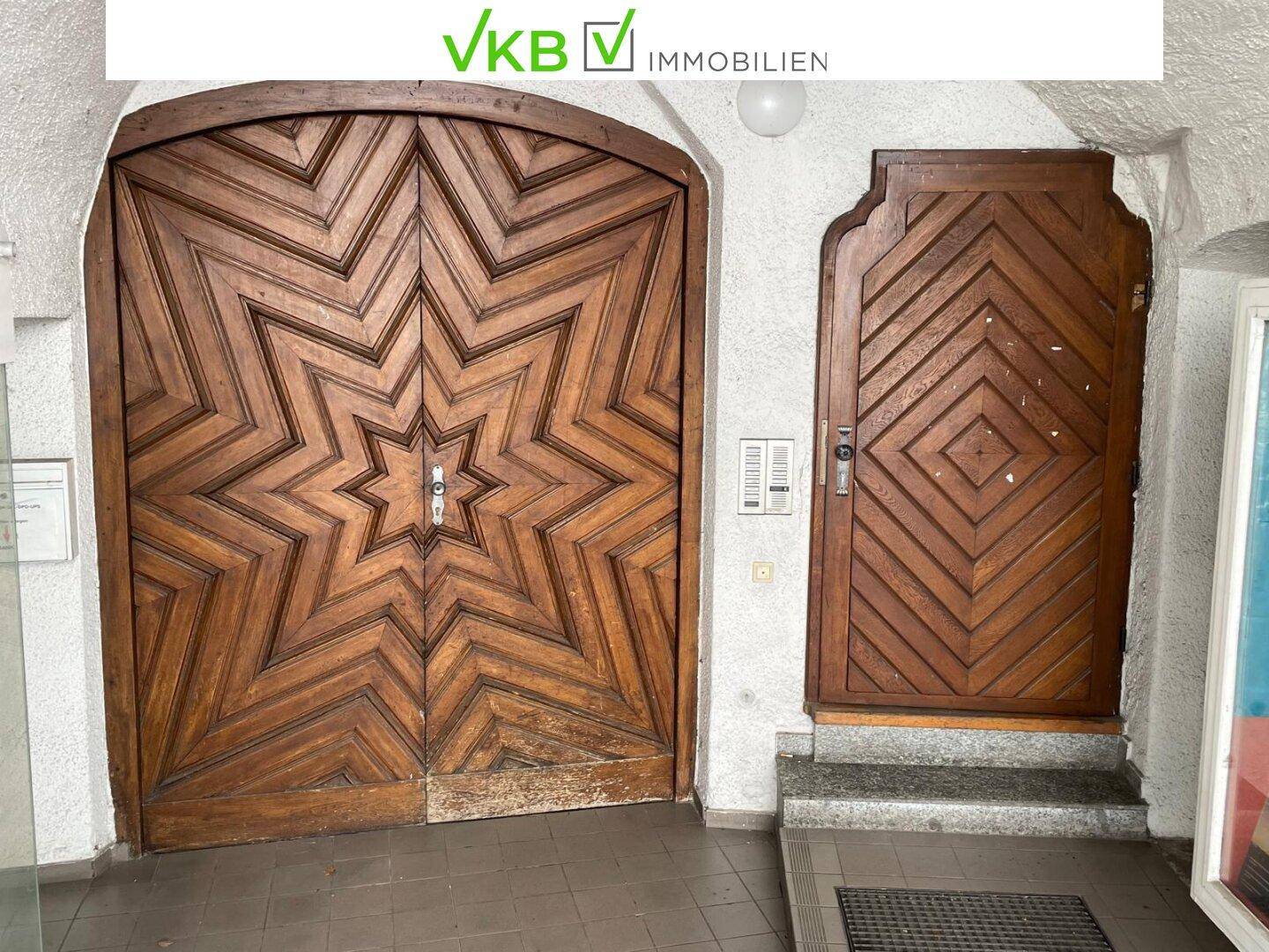 Historischer Eingangsbereich mit zwei kunstvoll geschnitzten Holztüren und Steinboden.