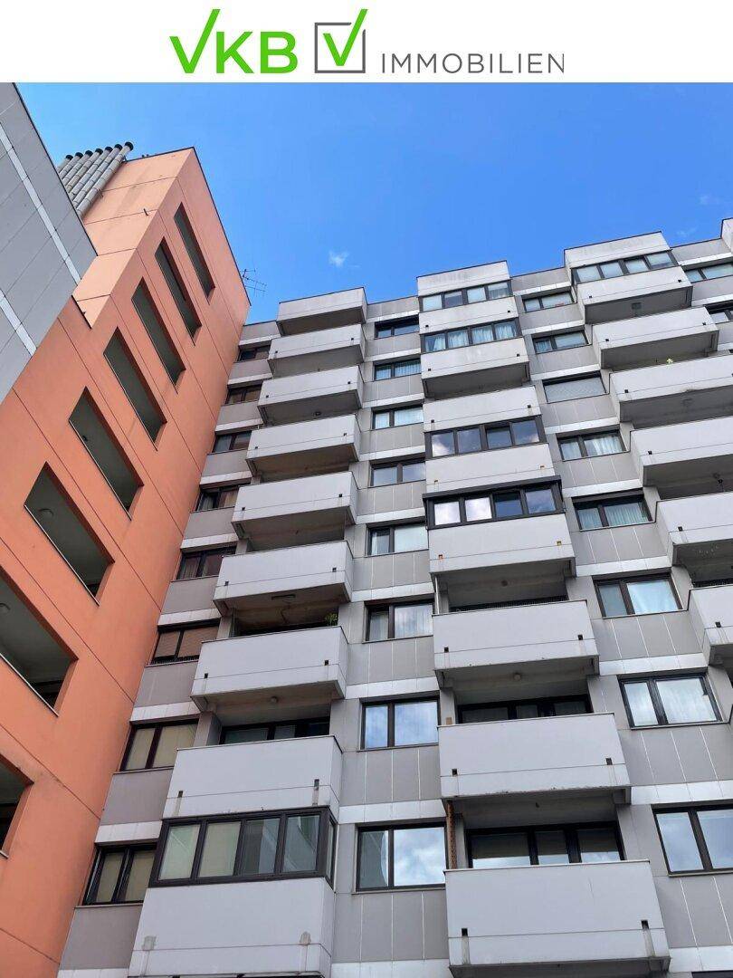 Hohes Wohngebäude mit zahlreichen Balkonen und einer markanten orangefarbenen Seitenfassade.