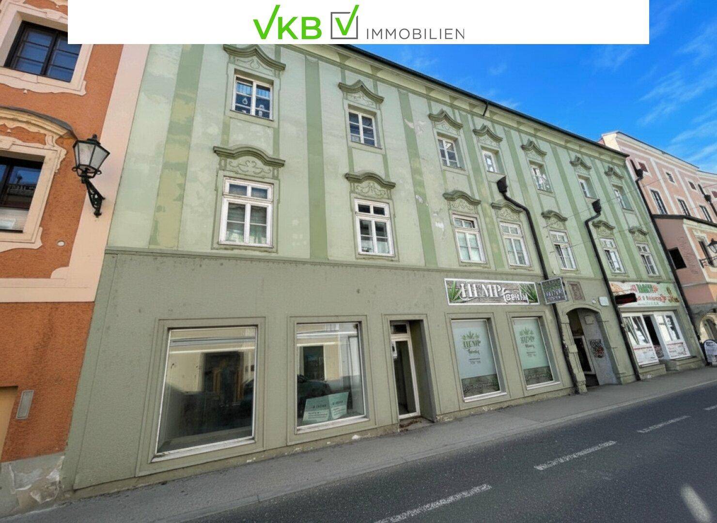 Historisches Gebäude mit Geschäften im Erdgeschoss und dekorativen Fenstern im Obergeschoss.