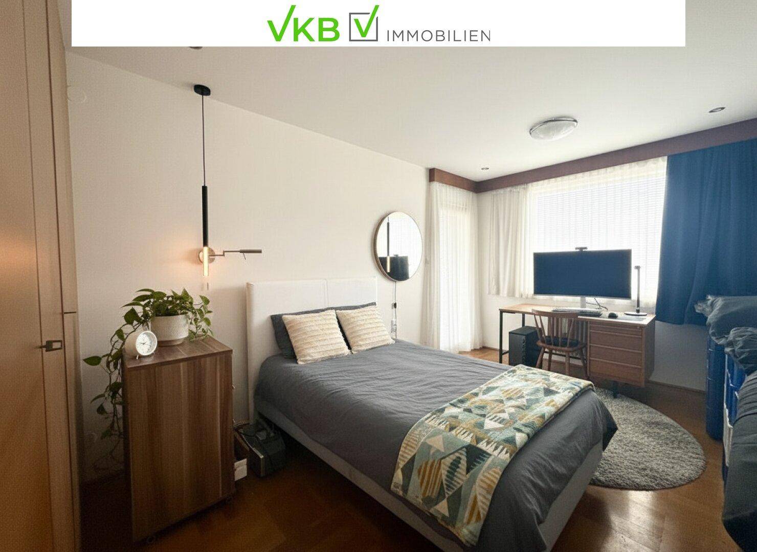 Gemütliches Schlafzimmer mit Doppelbett, Schreibtisch und einem runden Spiegel an der Wand.