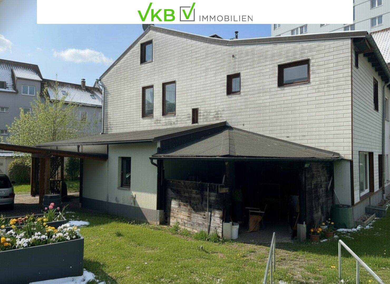 Rückansicht des Hauses mit Anbau, Carport und einem kleinen Gartenbereich.