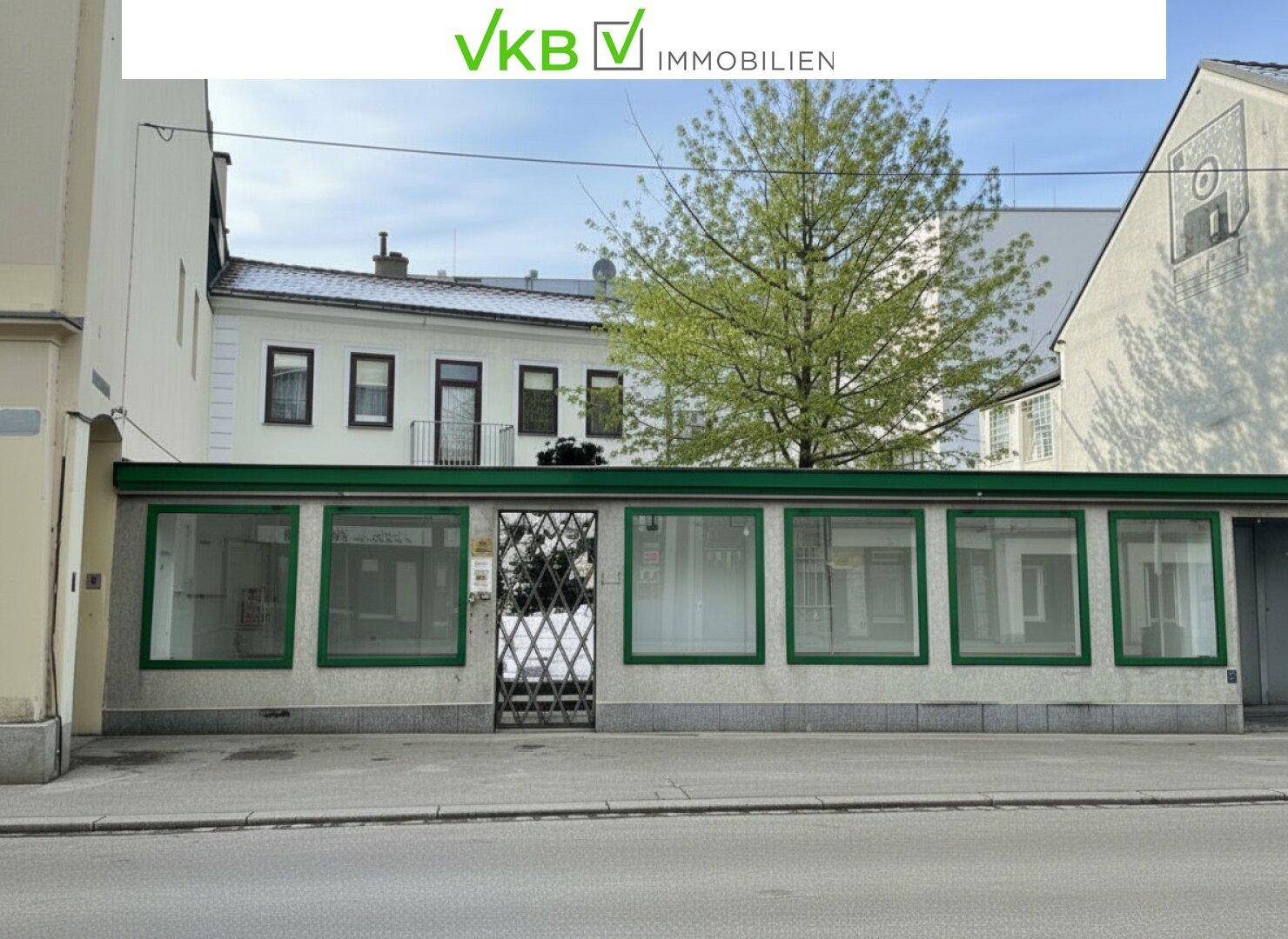 Straßenansicht mit einem Geschäftslokal im Vordergrund und dem Wohnhaus im Hintergrund.