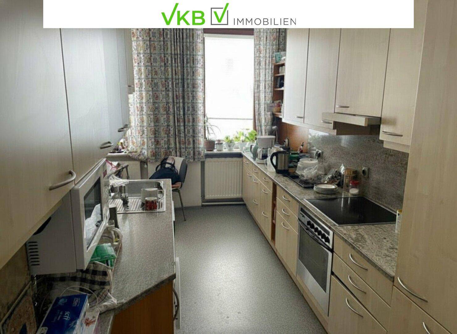 Funktionale Küche mit hellen Holzschränken, Granitarbeitsplatte und Fensterblick.