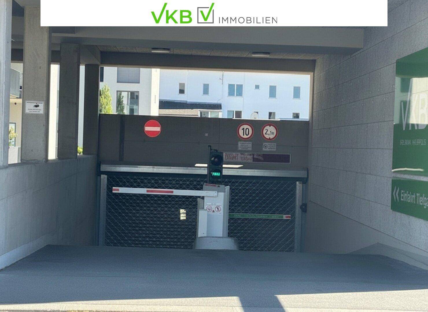 Einfahrt zur Tiefgarage mit Schranke, Höhenbegrenzung und Überwachungskamera für sicheren Zugang.