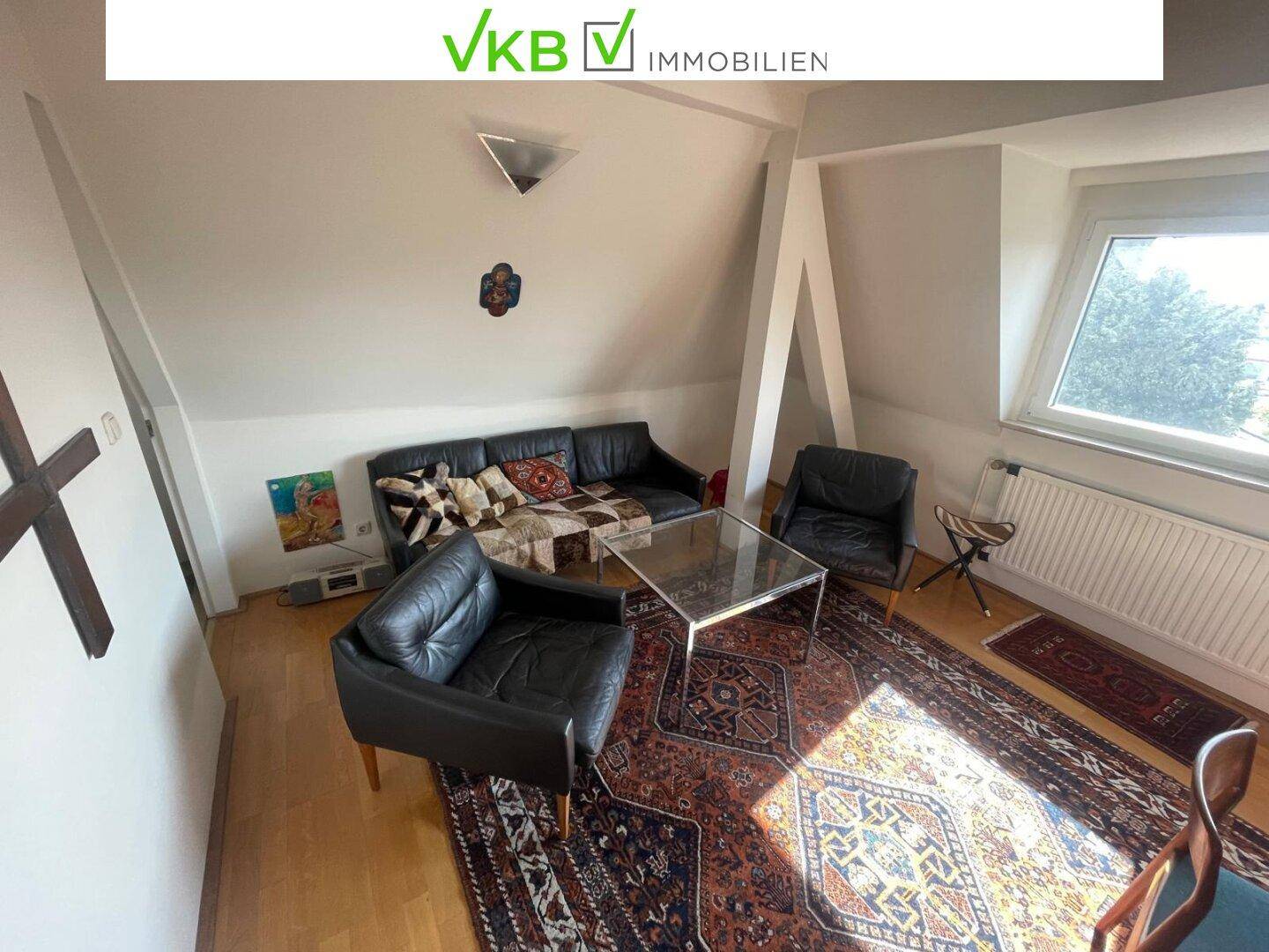 Geräumiges Wohnzimmer im Dachgeschoss mit Ledermöbeln, Teppichen und viel Tageslicht.
