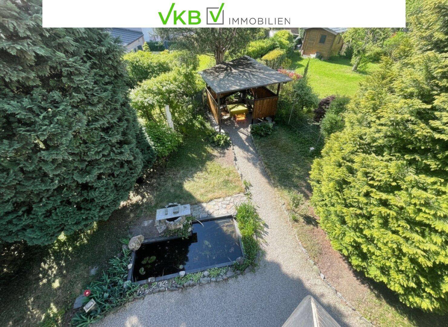 Gepflegter Garten mit einem Teich, einem Gartenpavillon und üppiger Bepflanzung.