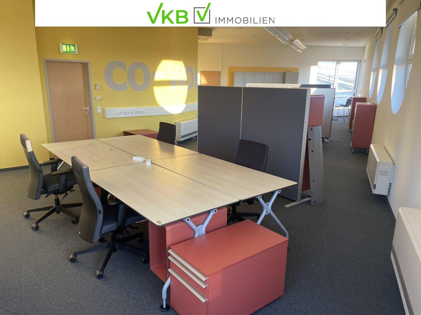 Großer Co-Working-Bürobereich mit mehreren Arbeitsplätzen, Schreibtischen und Bürostühlen.
