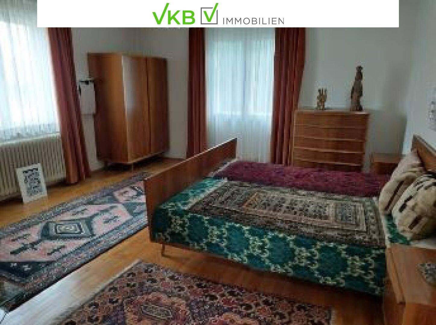 Helles Schlafzimmer mit Holzbetten, Kleiderschrank und Fenster mit Vorhängen.