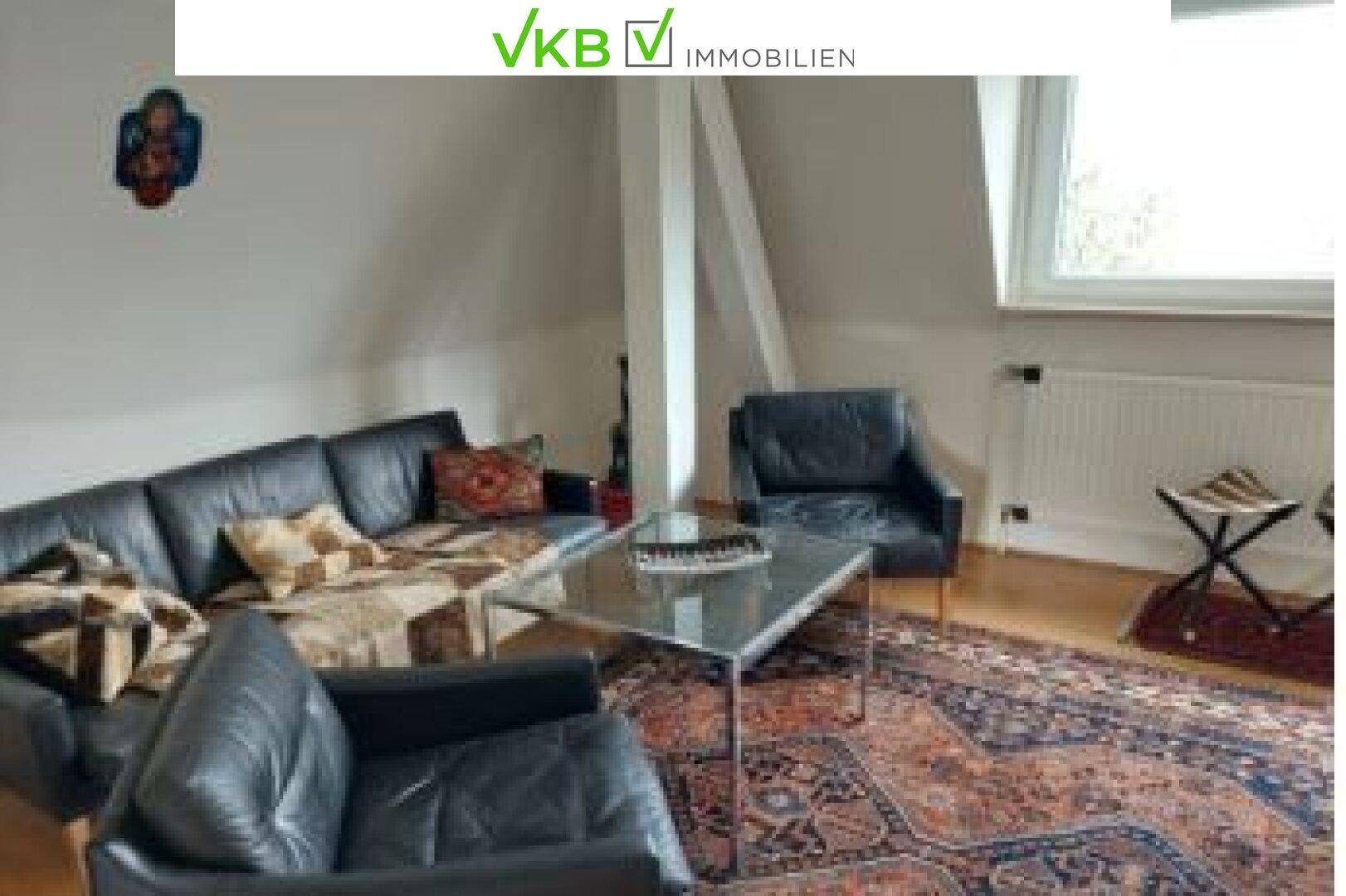 Gemütliches Wohnzimmer im Dachgeschoss mit Ledersofa, Teppich und schrägen Wänden.