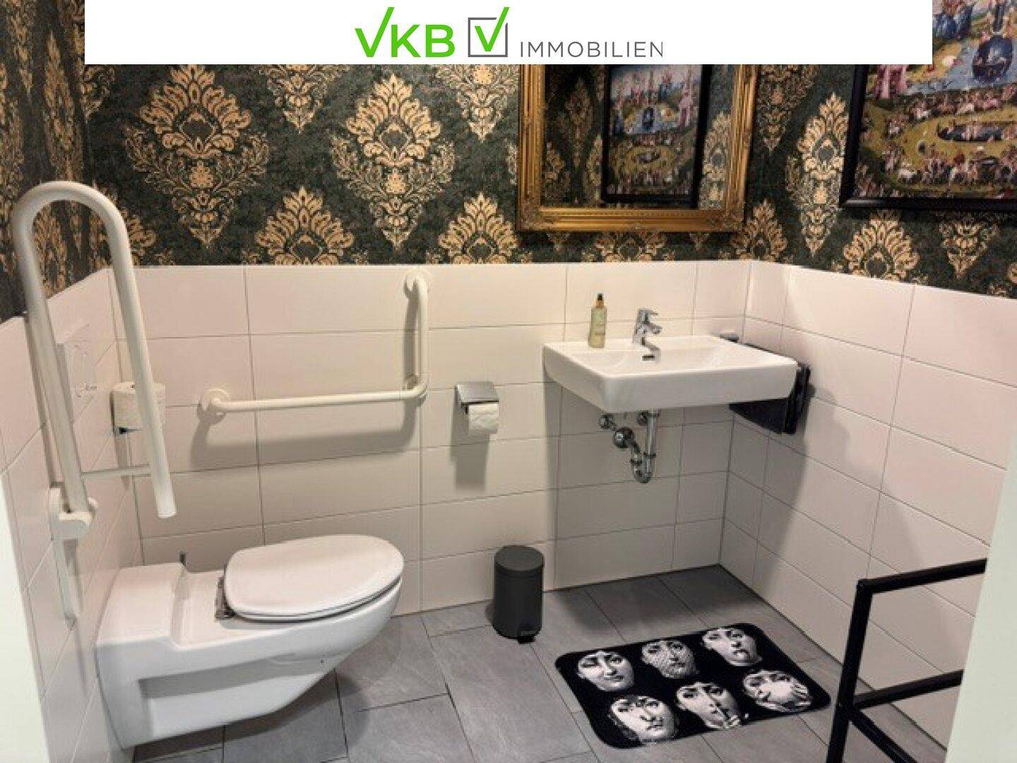 Barrierefreies Badezimmer mit Wand-WC, Waschbecken und Haltegriffen für zusätzliche Sicherheit.