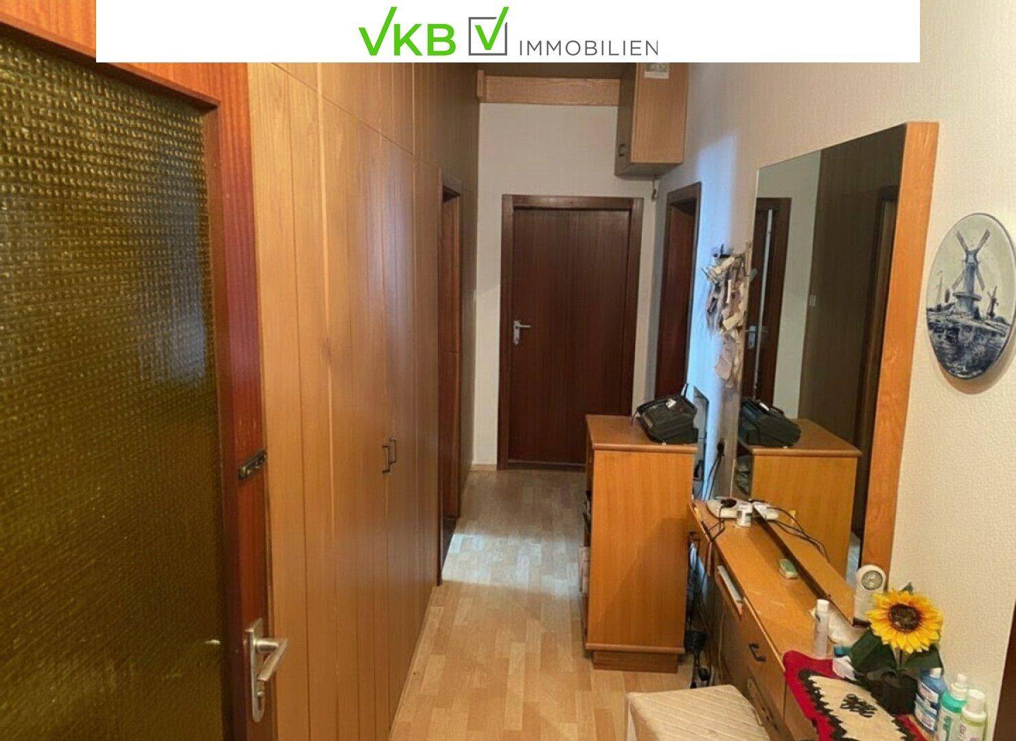 Flur mit Laminatboden, Einbauschränken aus Holz und einem großen Spiegel.