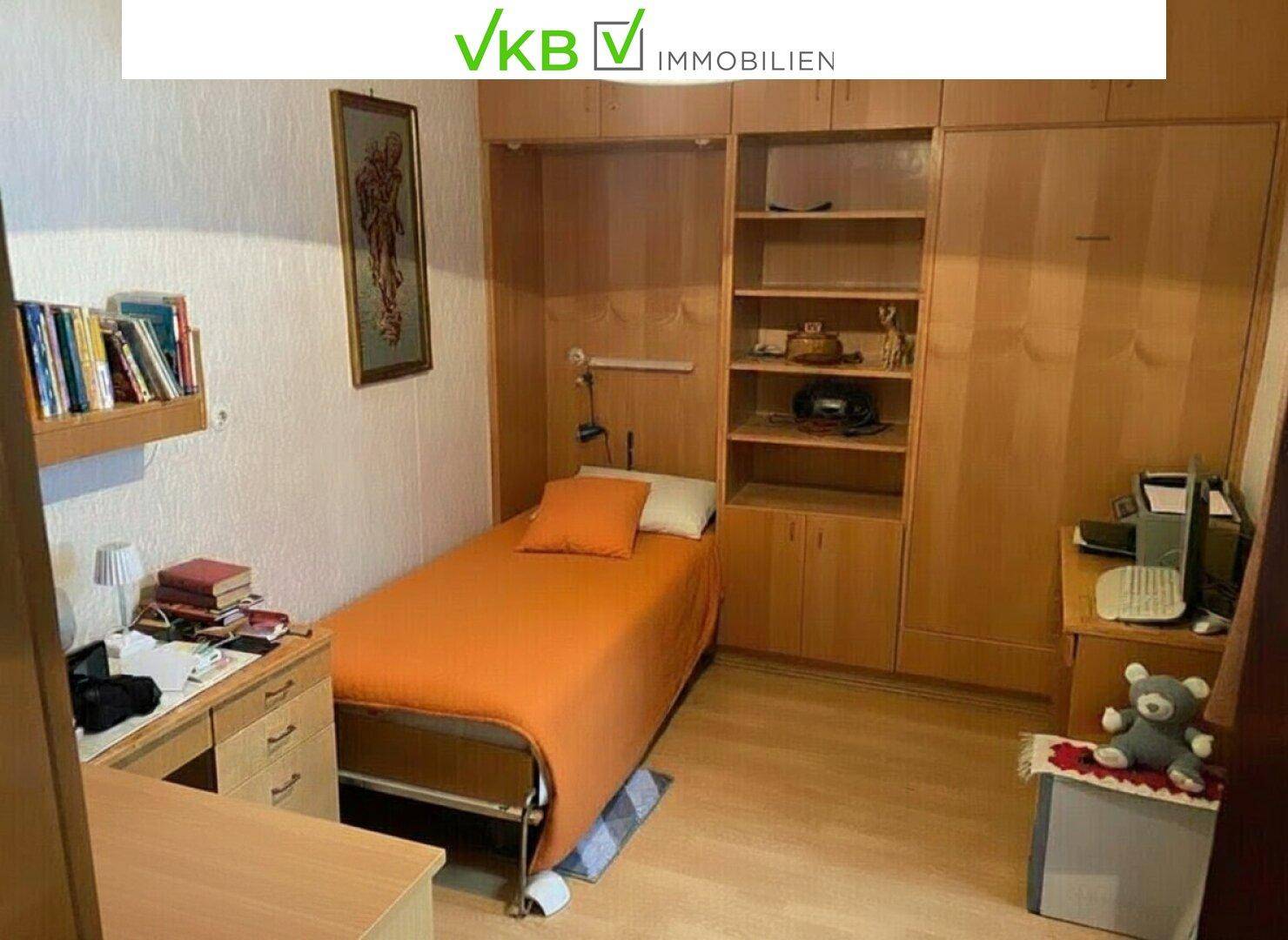 Schlafzimmer mit Einzelbett, Holzmöbeln und integrierten Regalen, funktional eingerichtet.