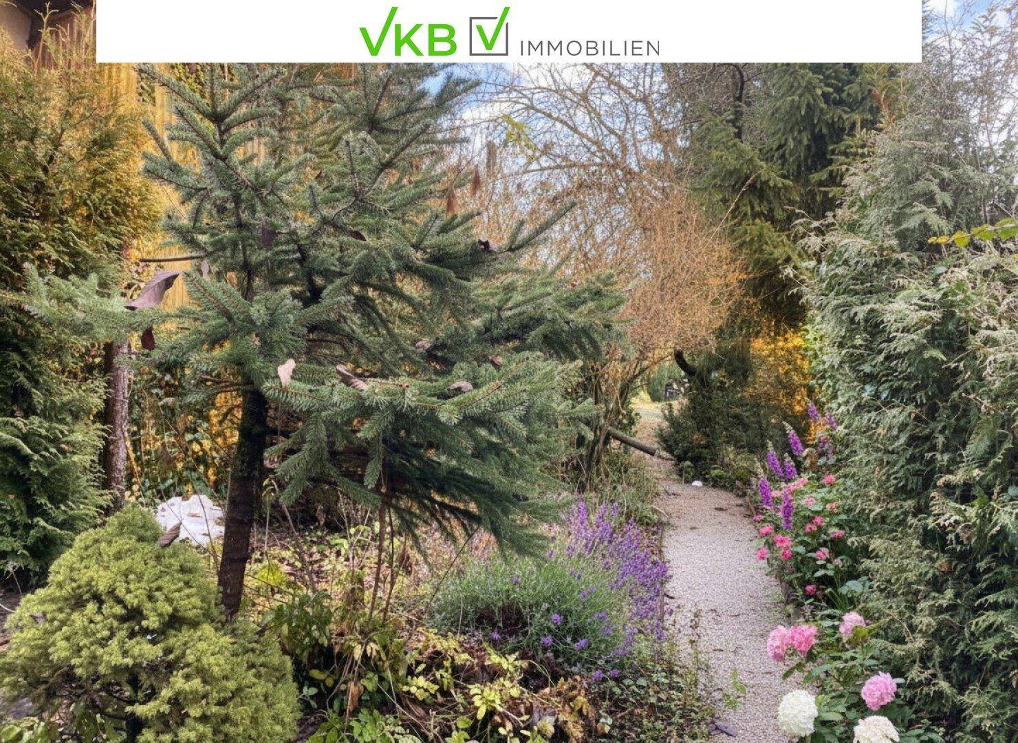 Idyllischer Gartenweg umgeben von üppiger Vegetation und blühenden Pflanzen.