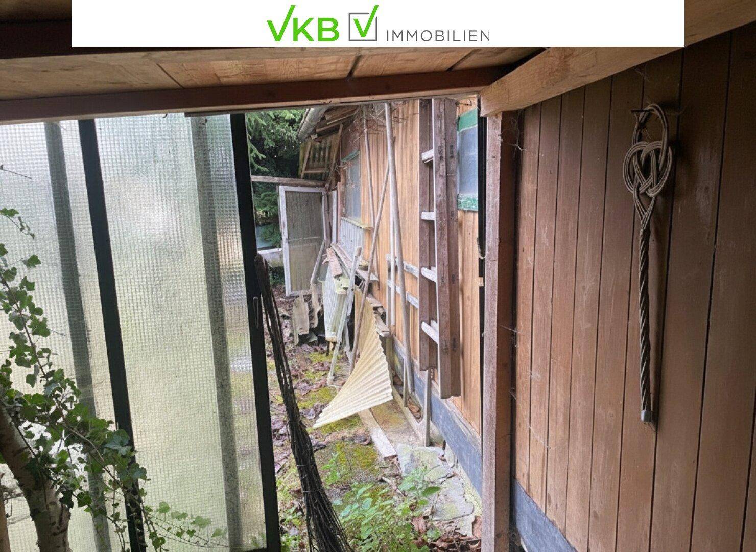 Außenansicht eines baufälligen Holzschuppens oder Anbaus im Gartenbereich.