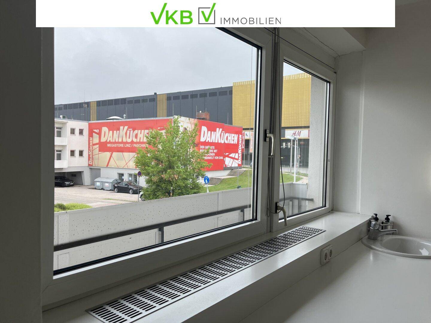 Großes Fenster bietet einen weiten Blick auf eine städtische Umgebung mit Geschäften und Gebäuden.