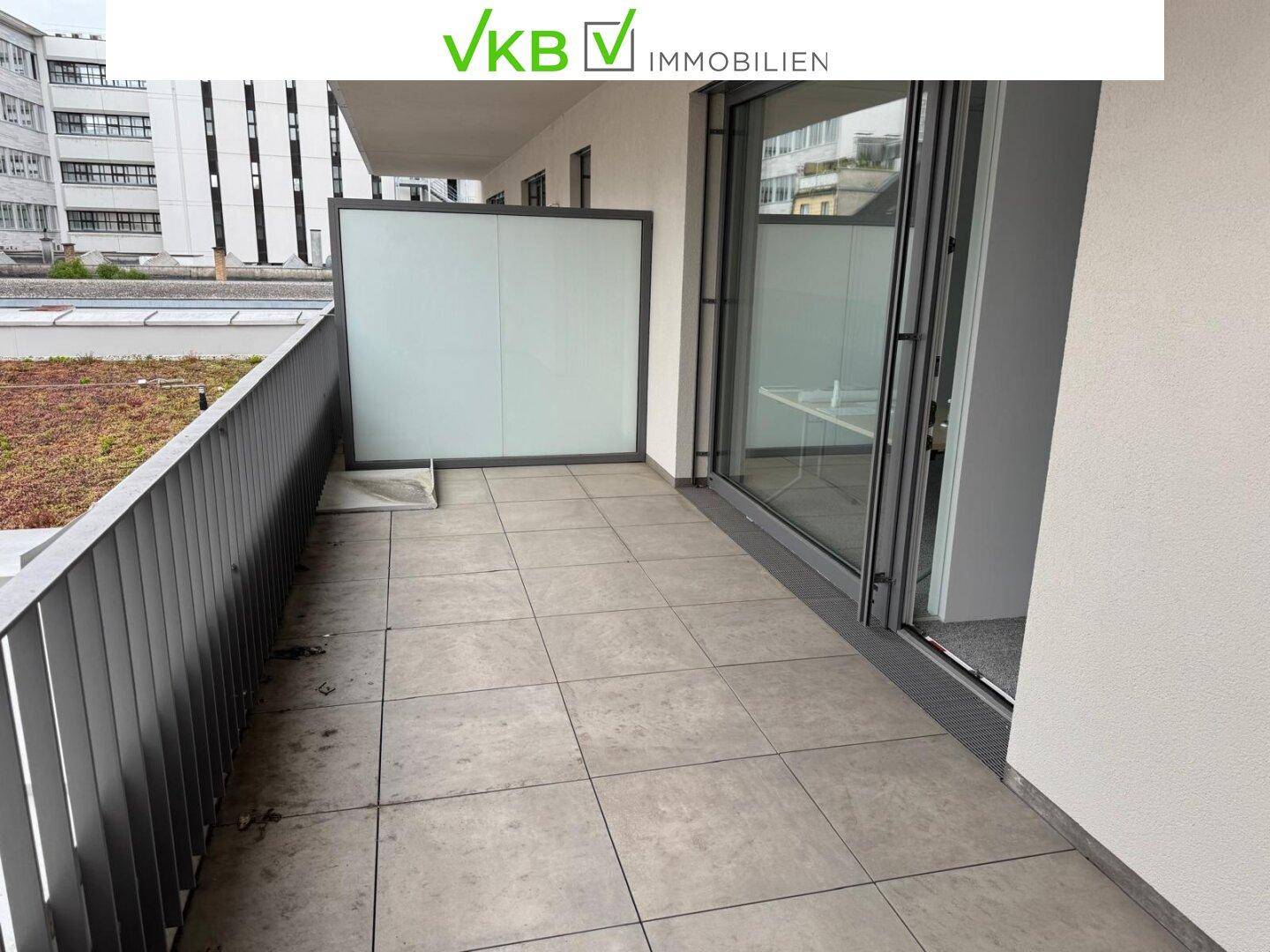 Moderner Balkon mit Fliesenboden und Milchglas-Sichtschutz, bietet einen Ausblick auf die Umgebung.