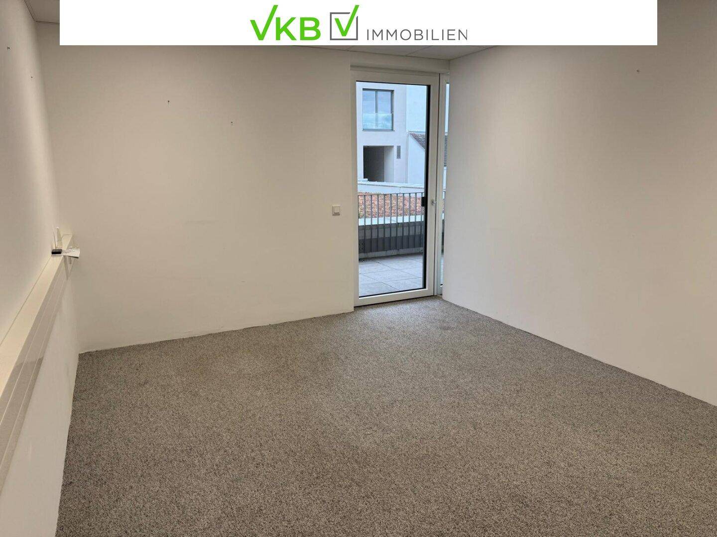 Helles Büro mit Teppichboden und Zugang zu einem Außenbereich, ideal für eine angenehme Arbeitsatmosphäre.