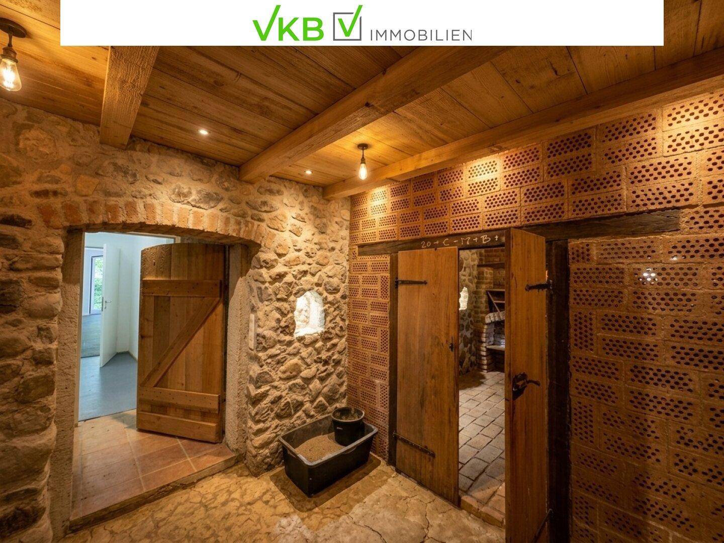 Eingangsbereich zum rustikalen Keller mit Steinwänden, Holztüren und Holzbalkendecke.